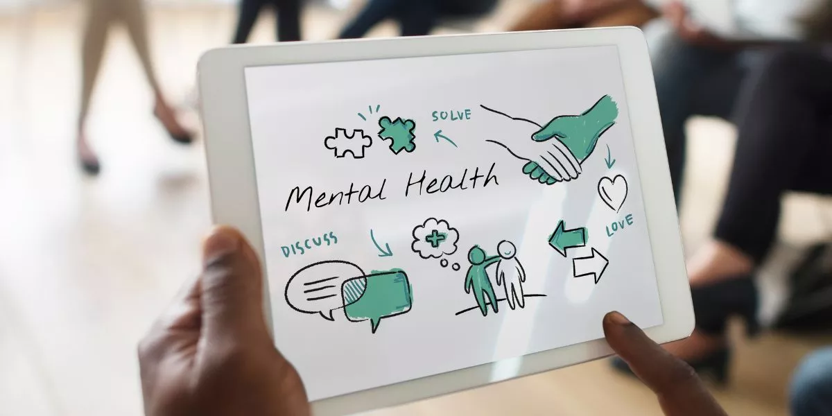 Hombre sostiene tablet con esquema de bienestar y salud mental en reunión de trabajo 