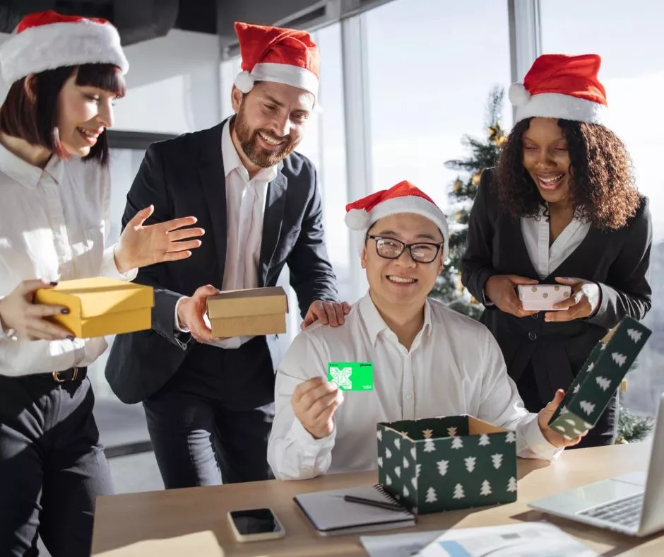 Grupo de colaboradores vestidos con gorros navideños celebran haber recibido una tarjeta Pluxee Navidad de regalo