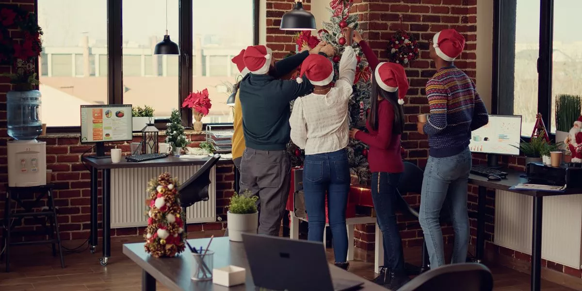 Colaboradores en la oficina decorando juntos el árbol navideño 