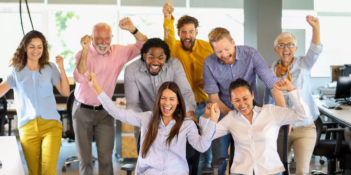 Equipo de trabajo celebrando en la oficina como parte de actividades de team building y formación de equipos.