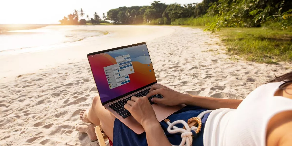 Persona trabajando en una laptop desde la playa durante sus vacaciones, reflejando la dificultad de desconexión laboral en Perú.