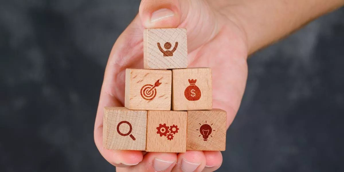 Mano sosteniendo bloques de madera en forma de pirámide con íconos que representan beneficios laborales peru