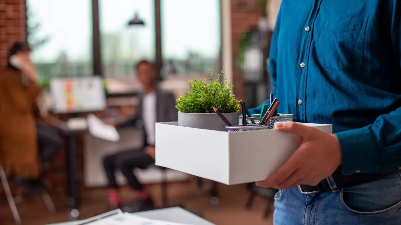 Colaborador juntando sus pertenencias en una caja luego de un proceso de offboarding en su empresa.