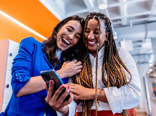 Dos colegas de trabajo ven juntas cómo funciona la tarjeta virtual de Pluxee.