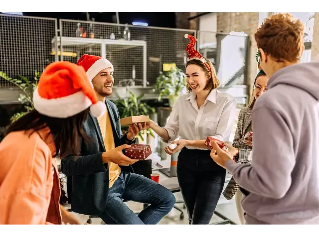 Personas intercambiando regalos durante una celebración corporativa, representando Pluxee Navidad como beneficio para colaboradores en fin de año.