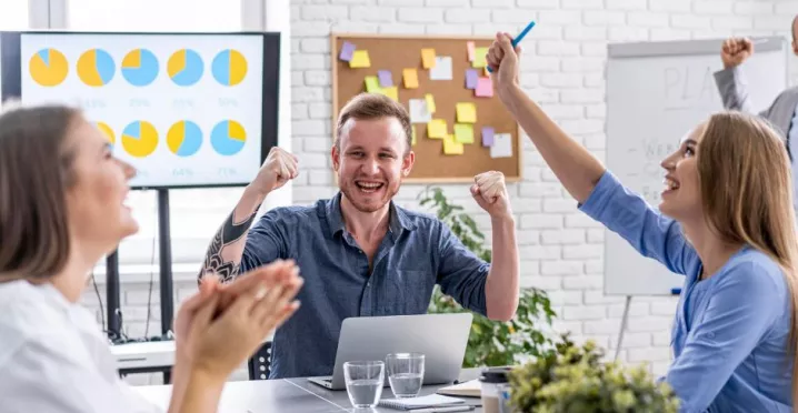 Jóvenes colaboradores celebrando que recibieron un incentivo laboral por el éxito de su proyecto