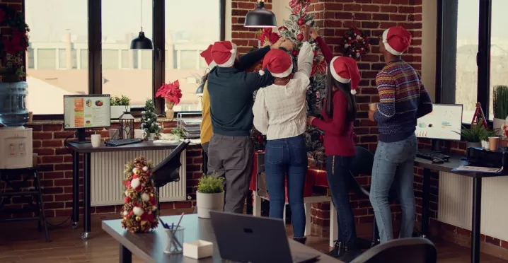 Colaboradores en la oficina decorando juntos el árbol navideño