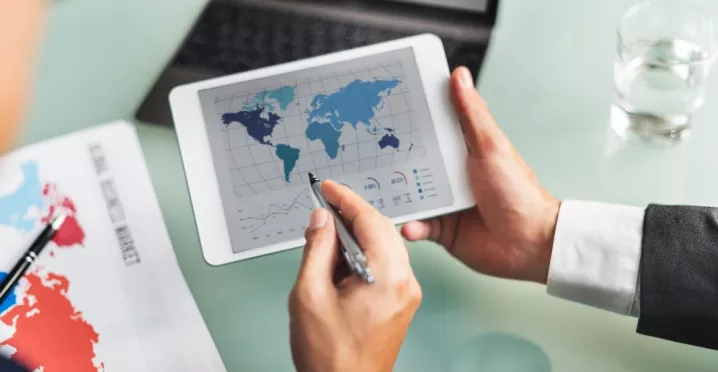 Profesional analizando datos del mercado global en una tablet durante la jornada laboral