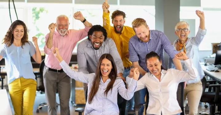 Equipo de trabajo celebrando en la oficina como parte de actividades de team building y formación de equipos.