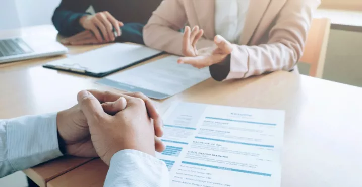 Entrevista de trabajo con revisión de un currículum vitae sobre la mesa, en un contexto de decisiones de contratación en empresas peruanas.