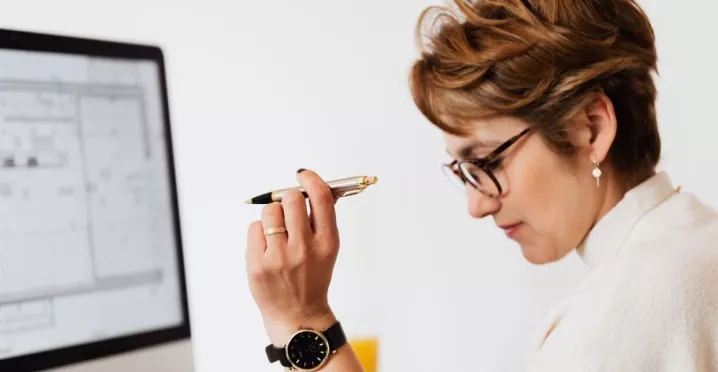 Mujer en oficina evaluando opciones de beneficios corporativos en Perú frente a una computadora, analizando propuestas de proveedores para empresas.