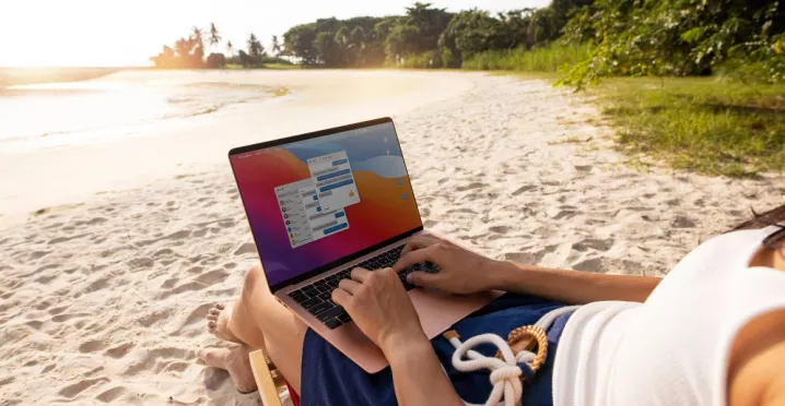 Persona trabajando en una laptop desde la playa durante sus vacaciones, reflejando la dificultad de desconexión laboral en Perú.