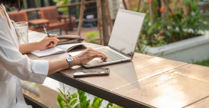 Mujer trabajando de forma remota desde una laptop en un espacio al aire libre.