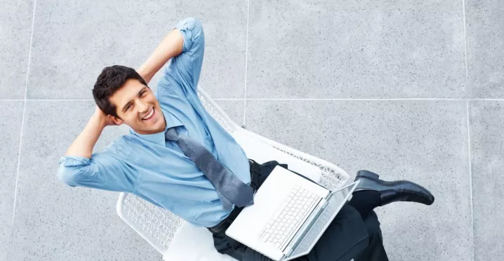Colaborador con una computadora portátil descansando durante su jornada, en representación de la semana laboral de 4 días.