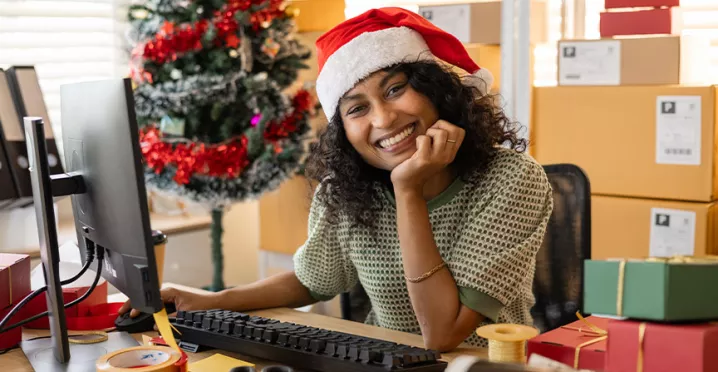 Una mujer con gorro navideño sonríe mientras trabaja.