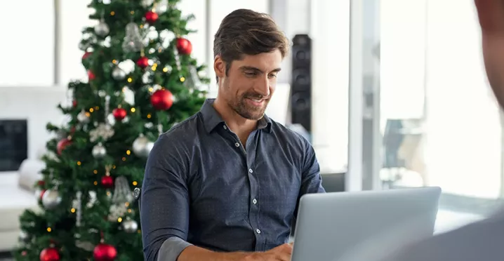 Hombre trabajando con un árbol de Navidad al fondo.
