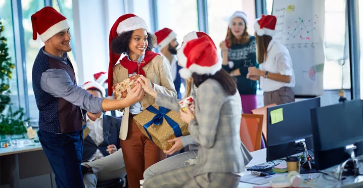 Compañeros de trabajo participan en un intercambio de regalos de Navidad en la oficina.