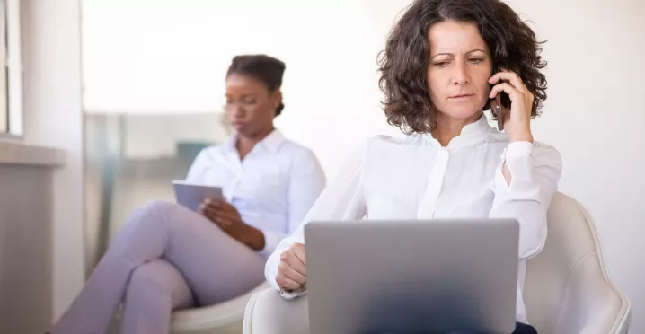 Mujer atiende una llamada con una computadora en su regazo, en una escena que ilustra los desafíos de la desconexión digital.