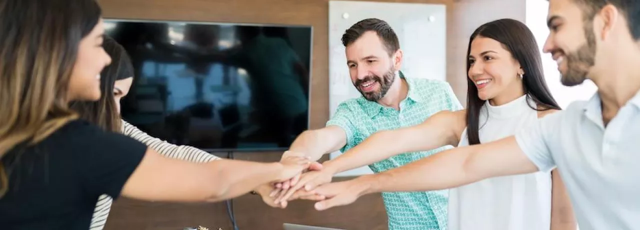 Equipo de trabajo colaborando con entusiasmo en una reunión, simbolizando beneficios laborales y salario emocional en empresas modernas
