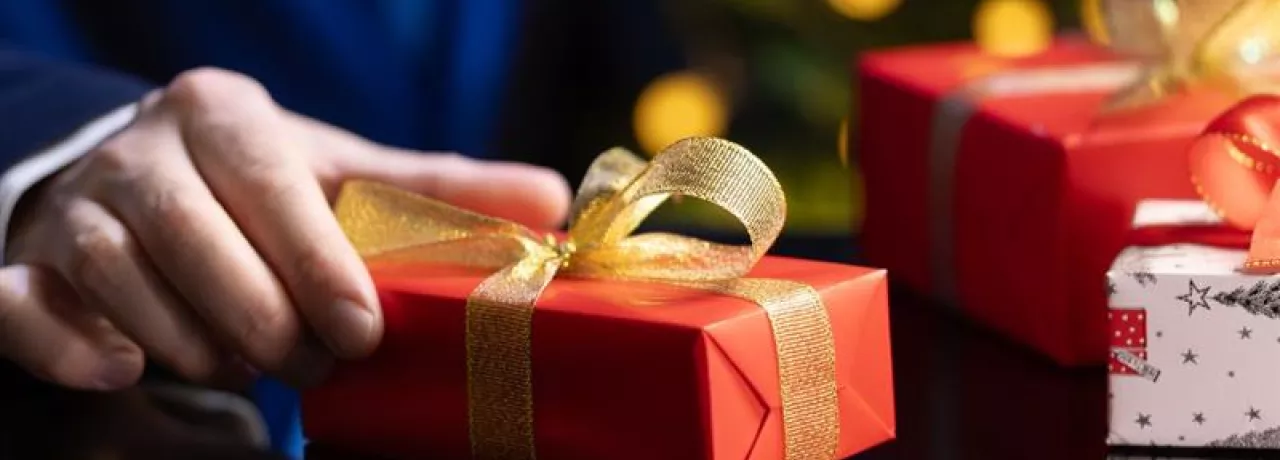 hombre sosteniendo un regalo navideño corporativo en su mano