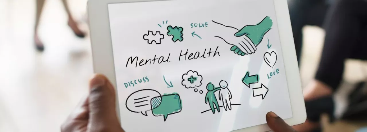 Hombre sostiene tablet con esquema de bienestar y salud mental en reunión de trabajo