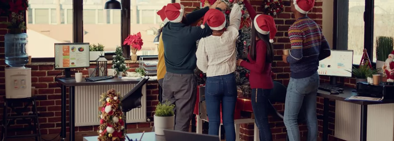 Colaboradores en la oficina decorando juntos el árbol navideño