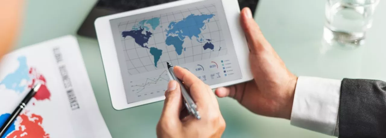 Profesional analizando datos del mercado global en una tablet durante la jornada laboral