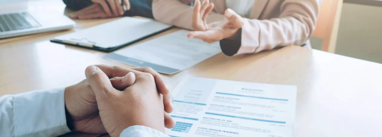 Entrevista de trabajo con revisión de un currículum vitae sobre la mesa, en un contexto de decisiones de contratación en empresas peruanas.