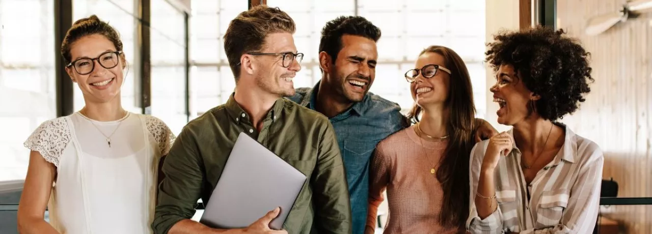 Equipo de trabajo motivado conversando en la oficina, ejemplo de cómo motivar a tu equipo de trabajo y fortalecer el clima laboral en Perú.