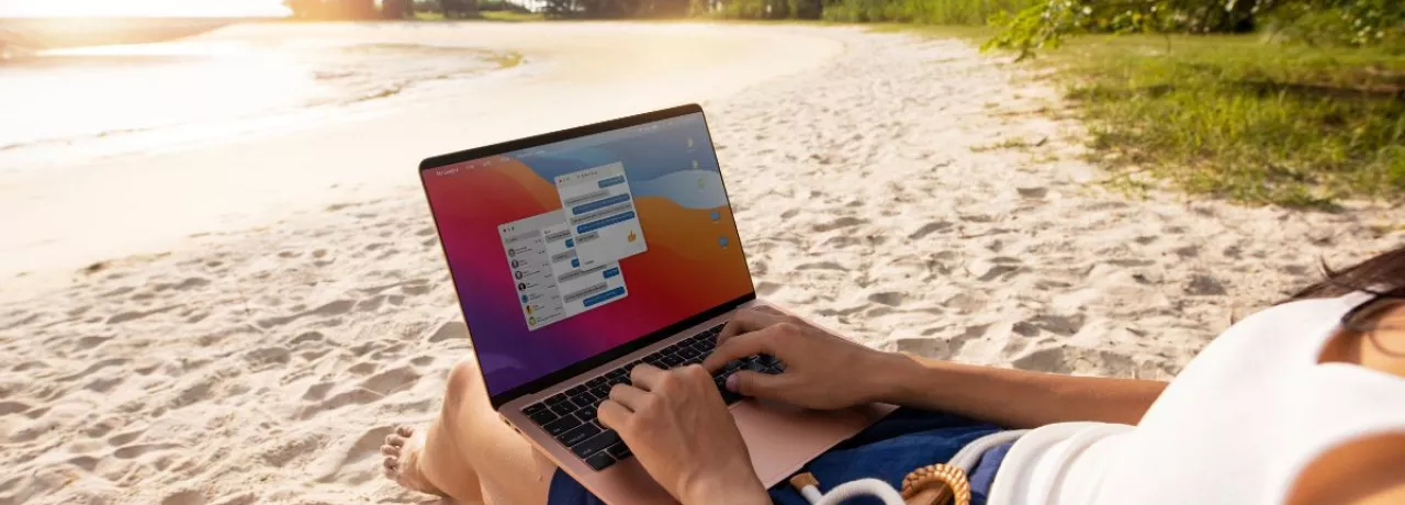 Persona trabajando en una laptop desde la playa durante sus vacaciones, reflejando la dificultad de desconexión laboral en Perú.