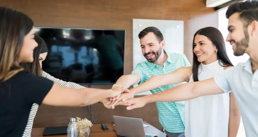 Equipo de trabajo colaborando con entusiasmo en una reunión, simbolizando beneficios laborales y salario emocional en empresas modernas