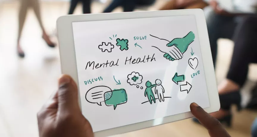 Hombre sostiene tablet con esquema de bienestar y salud mental en reunión de trabajo