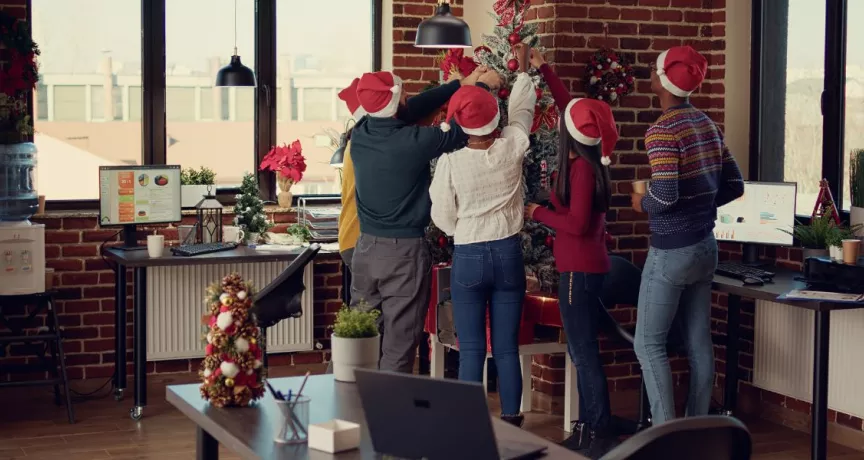 Colaboradores en la oficina decorando juntos el árbol navideño