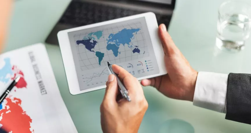 Profesional analizando datos del mercado global en una tablet durante la jornada laboral