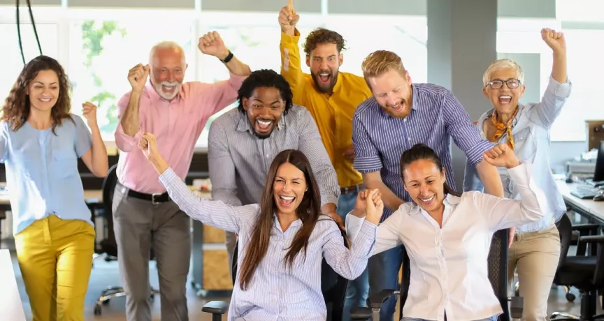 Equipo de trabajo celebrando en la oficina como parte de actividades de team building y formación de equipos.