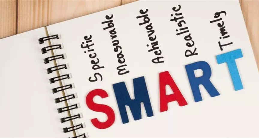Cuaderno con la palabra SMART y sus componentes, representando el método para definir objetivos SMART claros, medibles y alineados en las empresas.