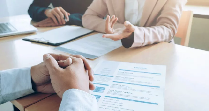 Entrevista de trabajo con revisión de un currículum vitae sobre la mesa, en un contexto de decisiones de contratación en empresas peruanas.