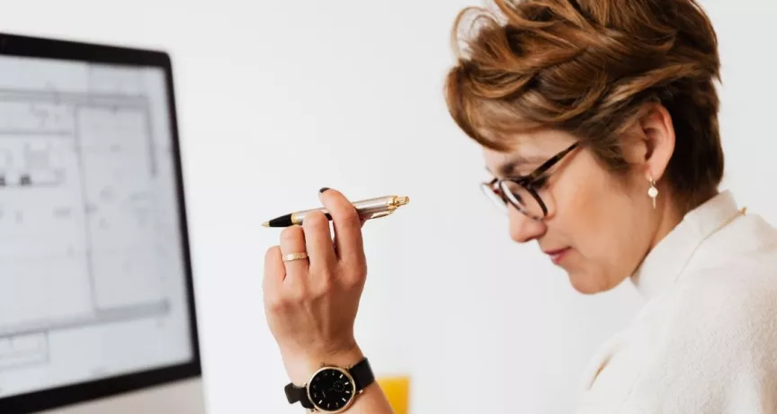 Mujer en oficina evaluando opciones de beneficios corporativos en Perú frente a una computadora, analizando propuestas de proveedores para empresas.