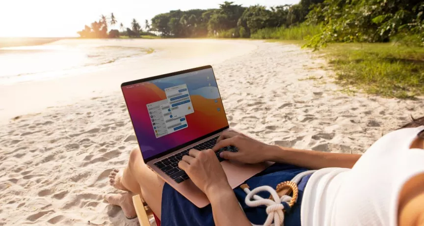 Persona trabajando en una laptop desde la playa durante sus vacaciones, reflejando la dificultad de desconexión laboral en Perú.