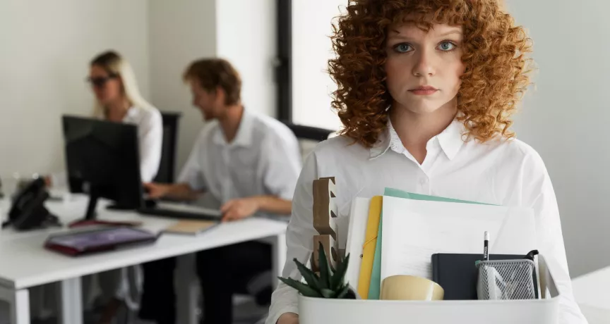 Colaboradora dejando la oficina con una caja de pertenencias tras una renuncia laboral relacionada con la rotación del personal en empresas.