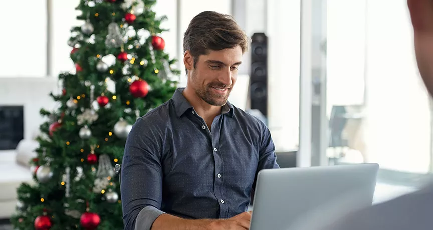 Hombre trabajando con un árbol de Navidad al fondo.