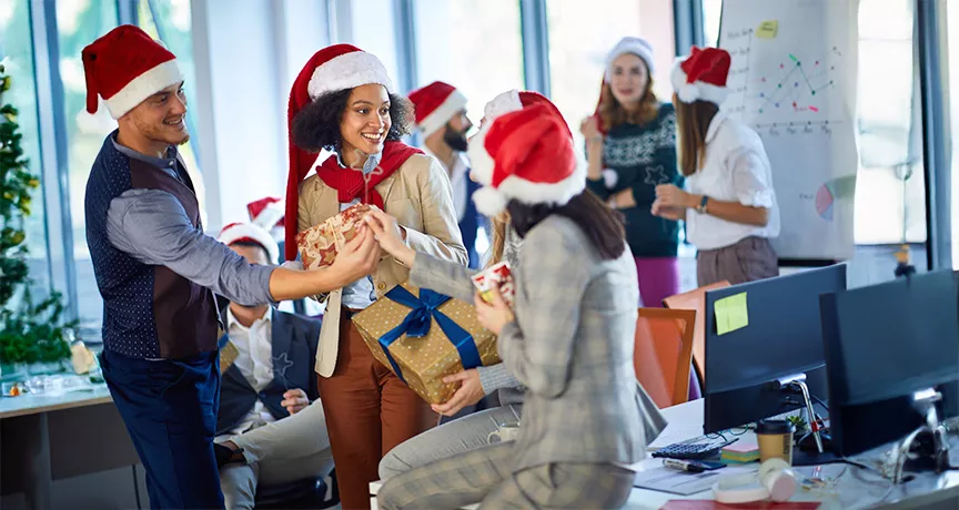 Compañeros de trabajo participan en un intercambio de regalos de Navidad en la oficina.