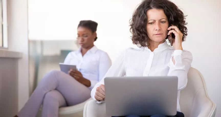 Mujer atiende una llamada con una computadora en su regazo, en una escena que ilustra los desafíos de la desconexión digital.
