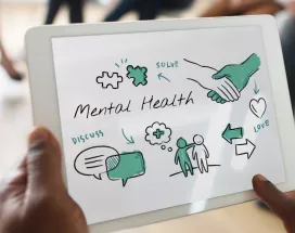 Hombre sostiene tablet con esquema de bienestar y salud mental en reunión de trabajo