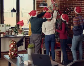 Colaboradores en la oficina decorando juntos el árbol navideño