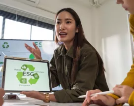 Profesional mostrando en una tablet una presentación sobre pilares ESG durante una reunión laboral, mientras explica estrategias de sostenibilidad al equipo.