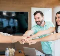 Equipo de trabajo colaborando con entusiasmo en una reunión, simbolizando beneficios laborales y salario emocional en empresas modernas