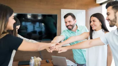 Equipo de trabajo colaborando con entusiasmo en una reunión, simbolizando beneficios laborales y salario emocional en empresas modernas