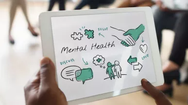 Hombre sostiene tablet con esquema de bienestar y salud mental en reunión de trabajo