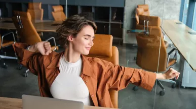 Mujer estirándose en una oficina moderna, representando bienestar laboral y equilibrio en el trabajo.